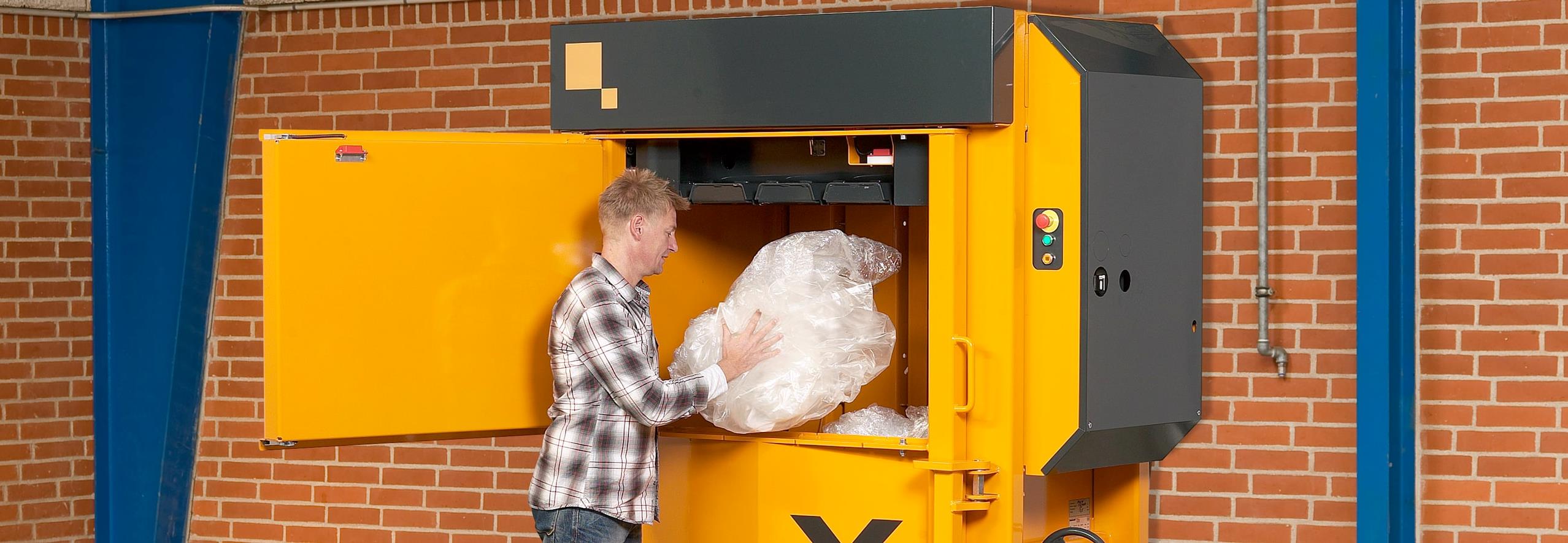 Man fills plastic waste into yellow baler