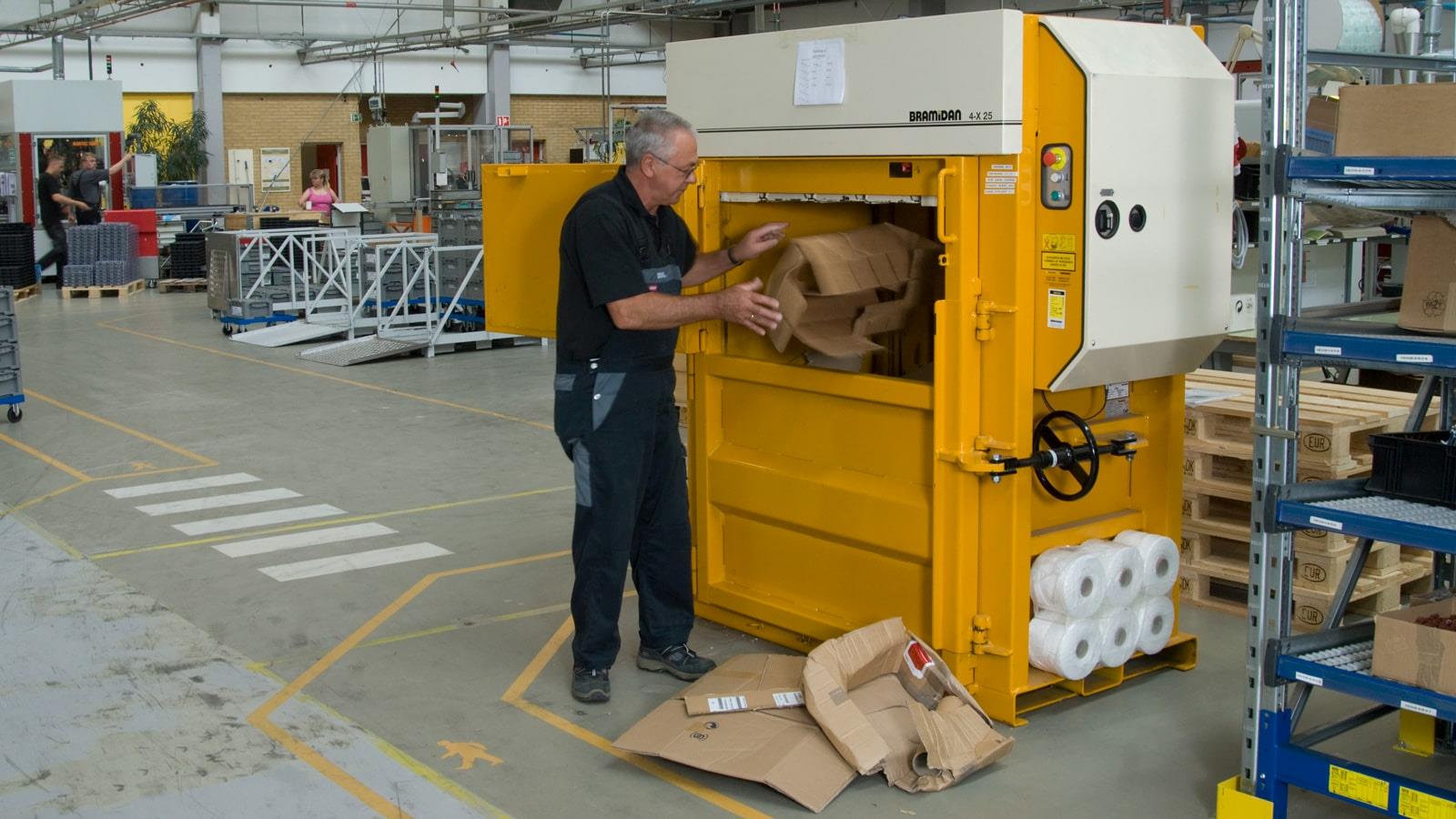 Sauer-Danfoss employee throws cardboard boxes into Bramidan baler