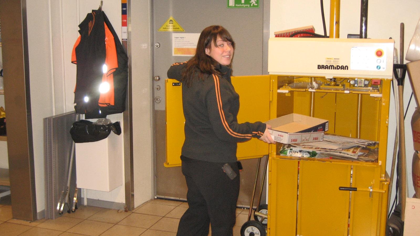 Female Statoil employee fills Bramidan baler with cardboard waste 