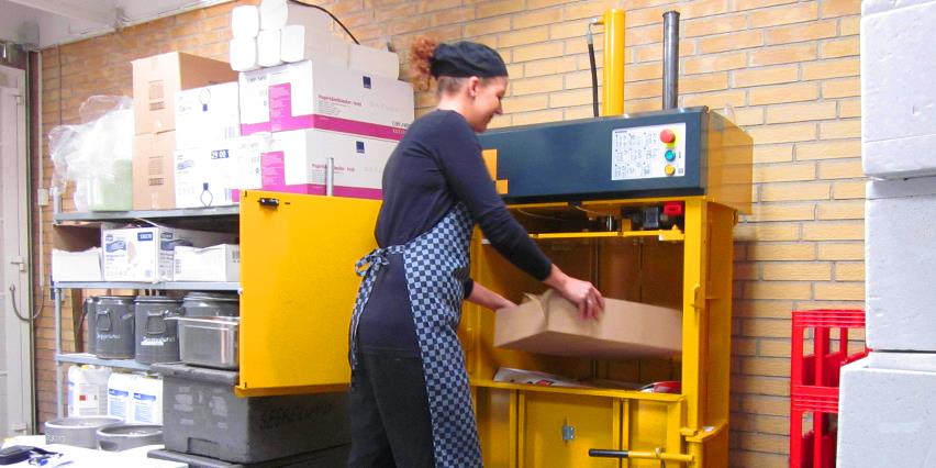 Employee at Seggelund Restaurant fills cardboard into small footprint baler